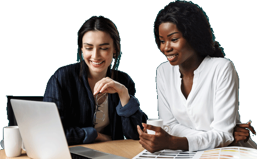 Duas mulheres sorridentes trabalhando em um laptop sobre uma mesa